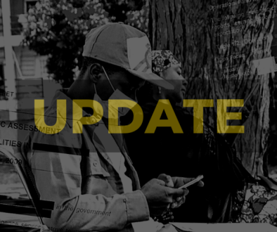 A man sitting on a chair under a tree checking his phone, with a woman in the background, in Nigeria. Image is superimposed with partly redacted State Security documents. Darkened, black and white with high contrast. 'UPDATE' appears in yellow. Photo credit: Ichie Opara / ALT Advisory (CC BY-NC-ND)